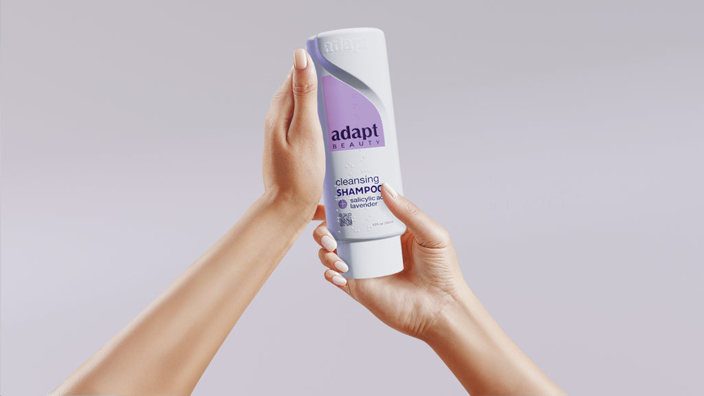 Person holding a bottle of Adapt shampoo against a plain background