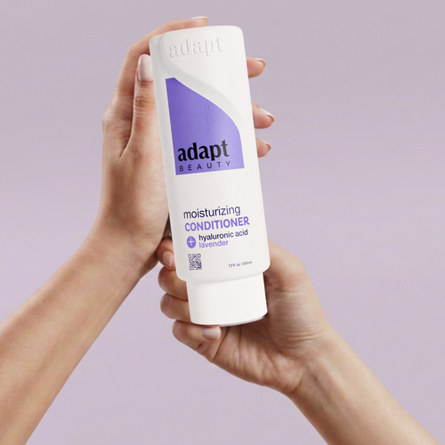 Person holding a bottle of Adapt Beauty moisturizing conditioner against a light purple background
